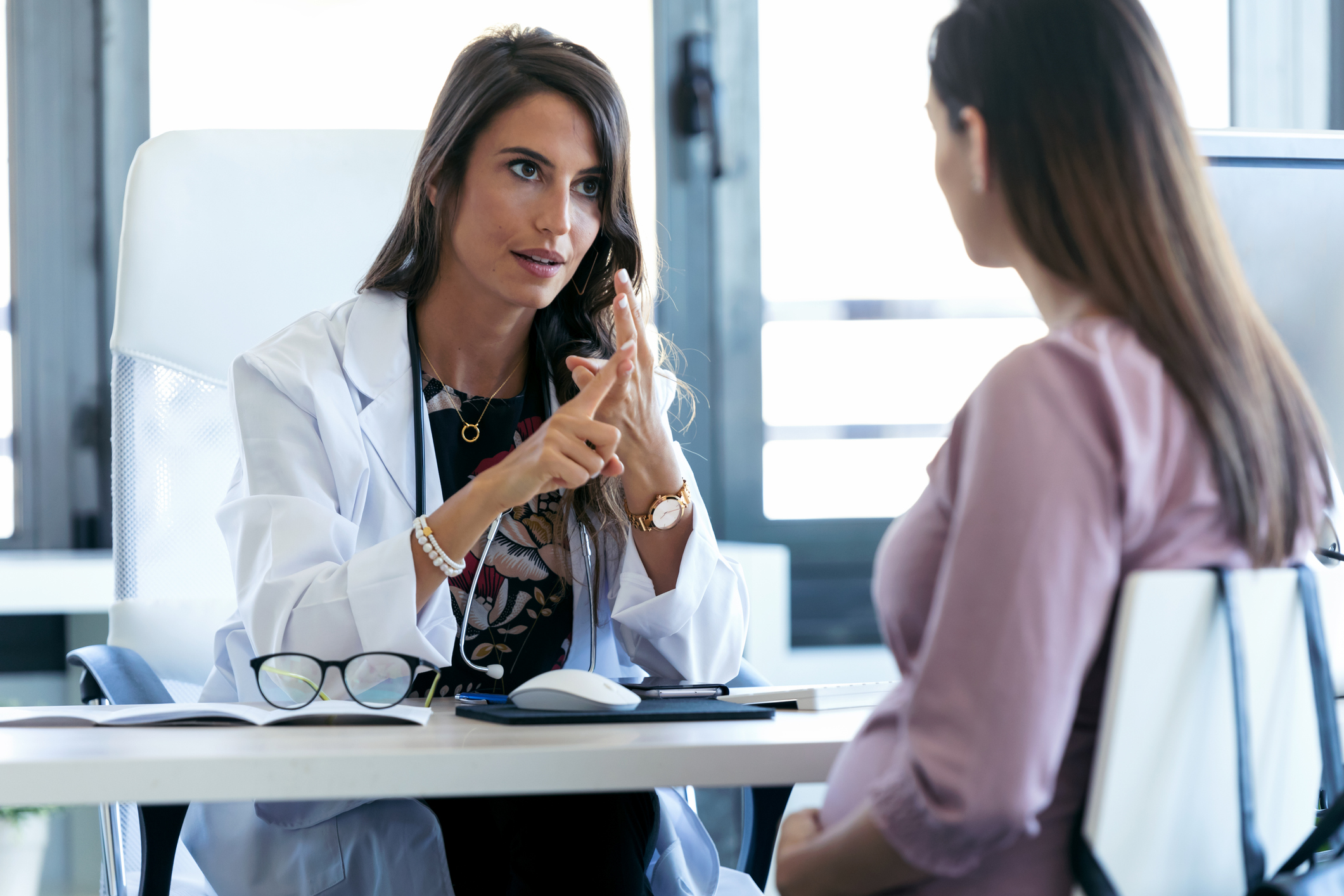 Healthcare professional speaking with pregnant woman in office